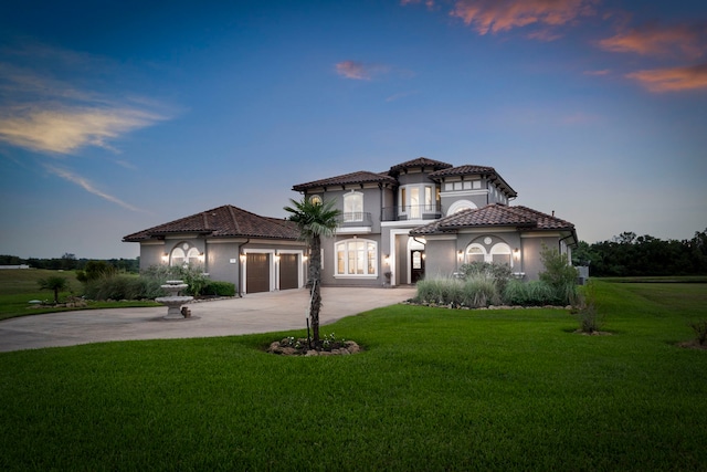 mediterranean / spanish-style home featuring a garage, concrete driveway, a front lawn, and a tile roof