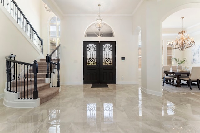 entrance foyer featuring ornamental molding, french doors, and an inviting chandelier