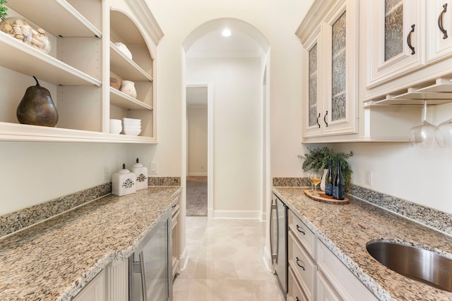 kitchen featuring crown molding, light stone countertops, and beverage cooler