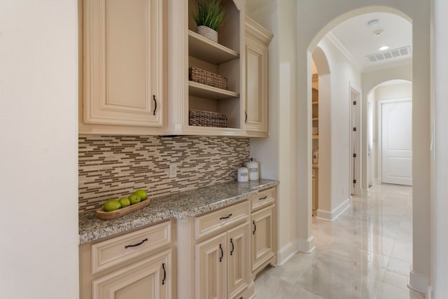 bar with arched walkways, visible vents, baseboards, backsplash, and crown molding