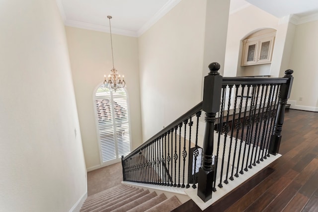 staircase with a notable chandelier, wood-type flooring, and crown molding