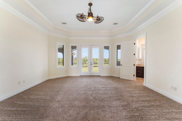 spare room featuring light carpet, a notable chandelier, ornamental molding, and a tray ceiling