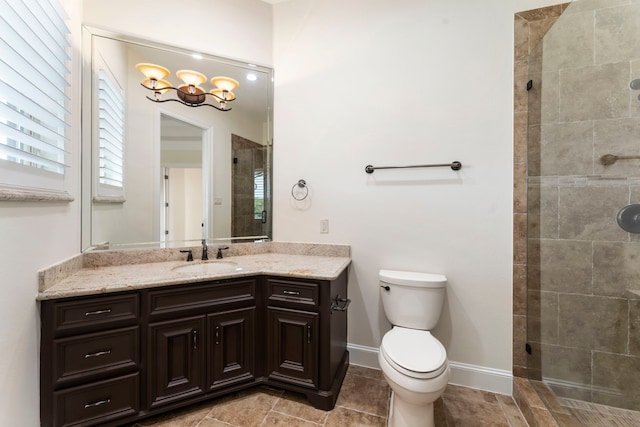 bathroom featuring toilet, a shower stall, vanity, and baseboards