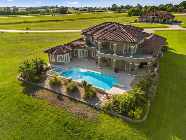 back of property with a tile roof, a patio, stucco siding, a pool with connected hot tub, and a balcony