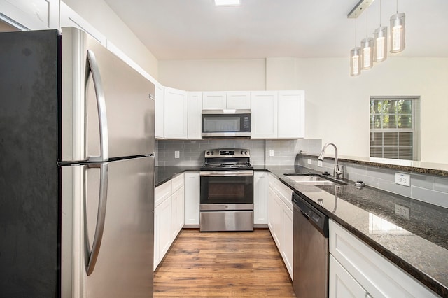 kitchen featuring stainless steel appliances, white cabinetry, hanging light fixtures, and sink