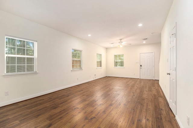 empty room featuring ceiling fan, plenty of natural light, and dark wood-type flooring