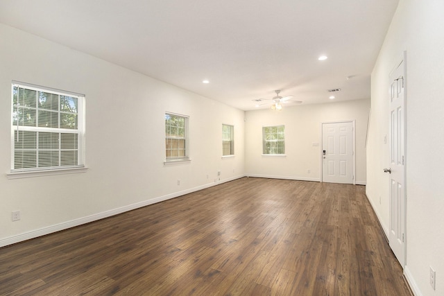 empty room featuring plenty of natural light, a ceiling fan, and dark wood-style flooring