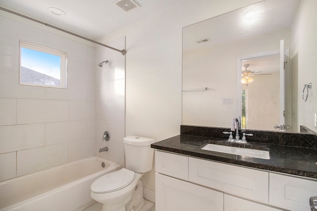 full bathroom with ceiling fan, tiled shower / bath, vanity, and toilet