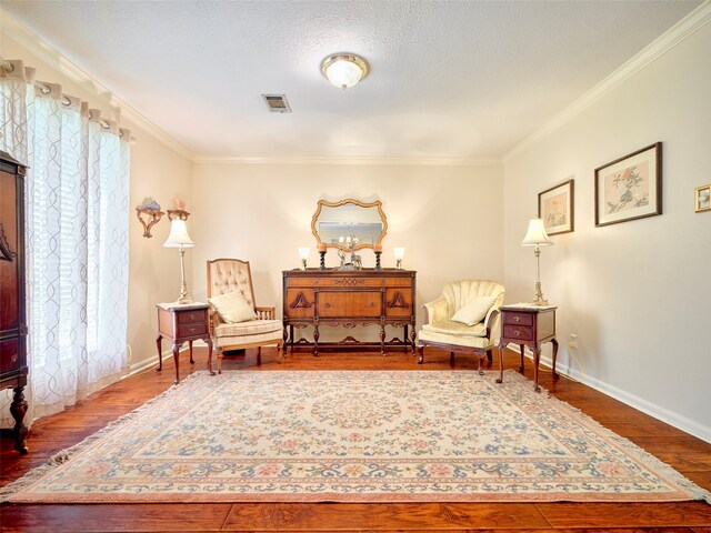 sitting room with wood-type flooring, a textured ceiling, and ornamental molding