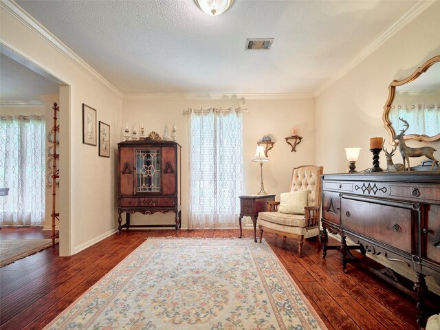 living area with a textured ceiling, dark hardwood / wood-style floors, and crown molding