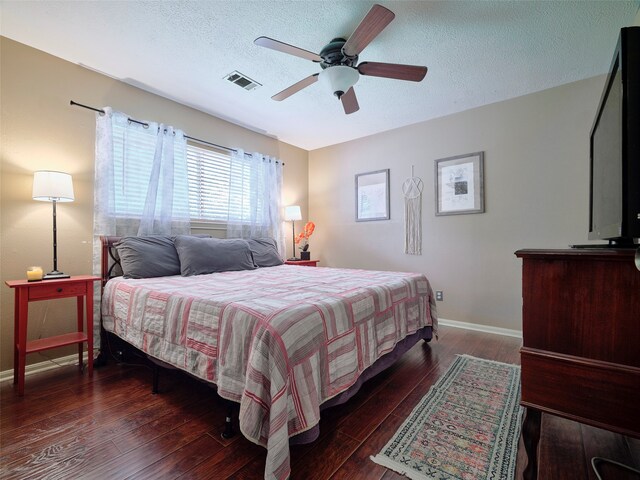 bedroom with ceiling fan, dark hardwood / wood-style flooring, and a textured ceiling