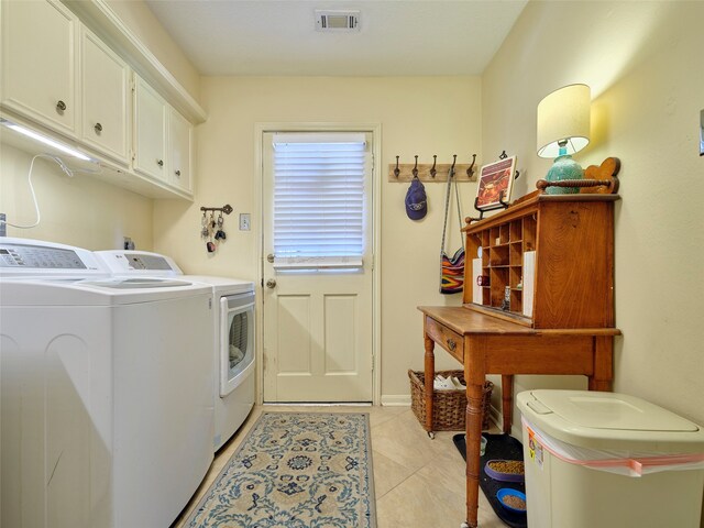 clothes washing area featuring light tile patterned flooring, cabinets, and washing machine and dryer