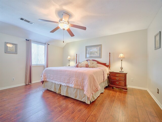 bedroom with ceiling fan, wood-type flooring, and a textured ceiling