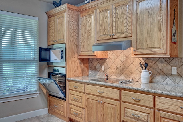 kitchen featuring a healthy amount of sunlight, oven, cooktop, and custom range hood