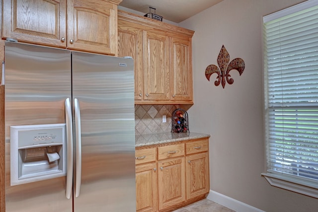 kitchen with light brown cabinets, stainless steel fridge, and tasteful backsplash