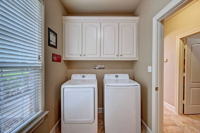 laundry area with cabinets, light tile patterned floors, and washer and clothes dryer