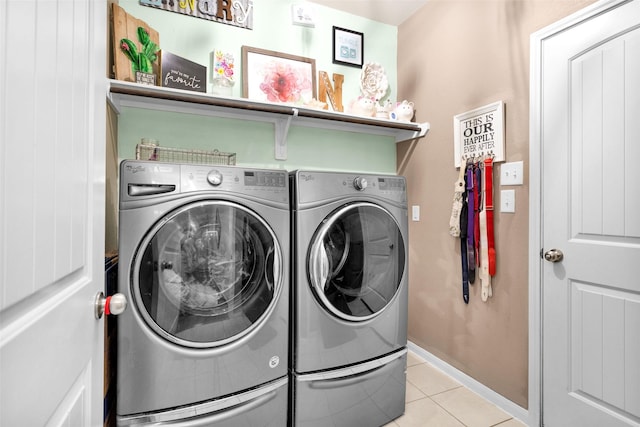 laundry area featuring laundry area, light tile patterned flooring, washing machine and dryer, and baseboards