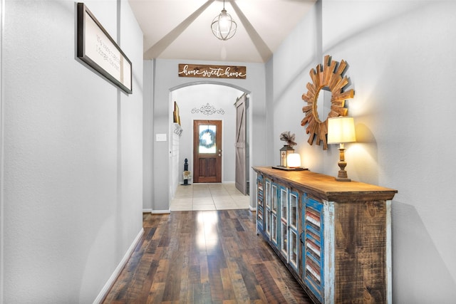 foyer featuring arched walkways, baseboards, and wood-type flooring