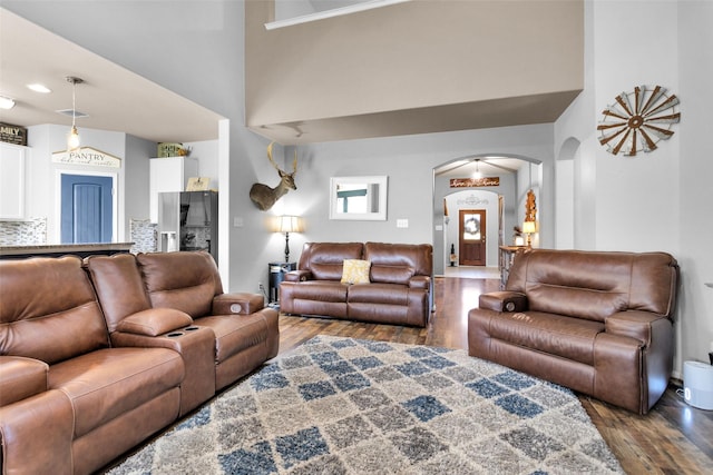 living room featuring a high ceiling, wood finished floors, and arched walkways