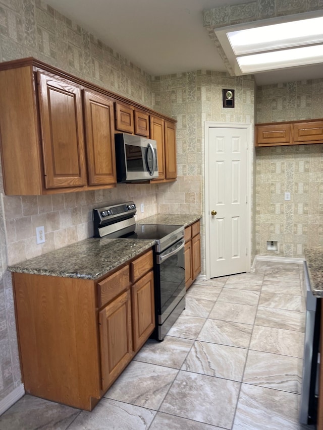 kitchen with stainless steel appliances and dark stone countertops