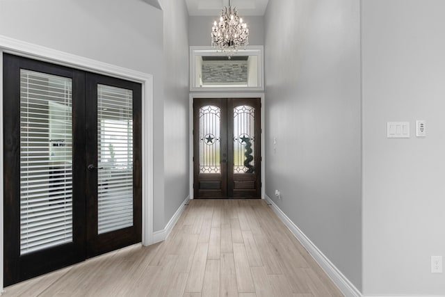 foyer entrance featuring french doors, a chandelier, and light hardwood / wood-style floors