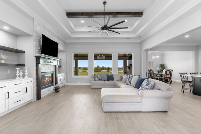 living room featuring a stone fireplace, beamed ceiling, light wood-type flooring, ceiling fan, and ornamental molding