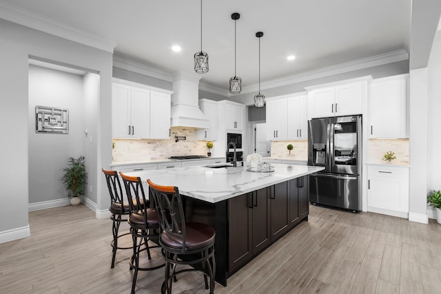 kitchen with a spacious island, appliances with stainless steel finishes, custom range hood, and white cabinetry