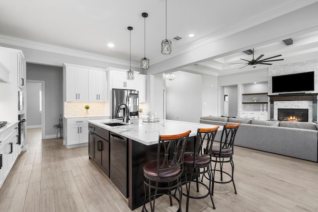 kitchen featuring light hardwood / wood-style floors, a kitchen island with sink, hanging light fixtures, a fireplace, and ceiling fan