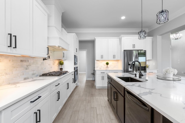 kitchen featuring sink, decorative light fixtures, light hardwood / wood-style flooring, white cabinetry, and appliances with stainless steel finishes