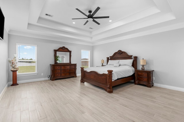 bedroom featuring light wood-type flooring, a tray ceiling, ceiling fan, and crown molding