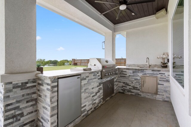 view of patio featuring ceiling fan, sink, a grill, and exterior kitchen