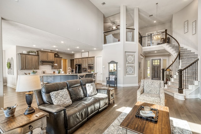 living room with a high ceiling, ceiling fan, and dark wood-type flooring