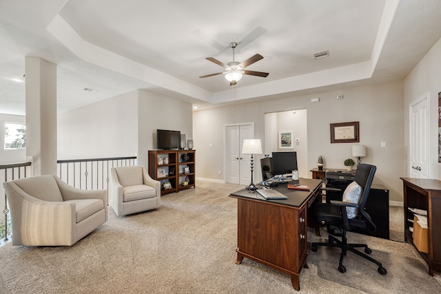 office with ceiling fan, a raised ceiling, and light carpet