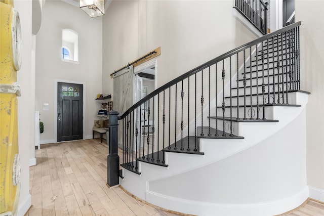 entryway with a high ceiling, a barn door, and hardwood / wood-style floors