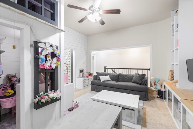 carpeted living room with ceiling fan and wood walls