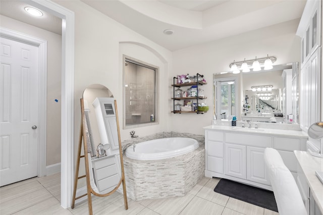 bathroom with vanity, a relaxing tiled tub, and tile patterned floors