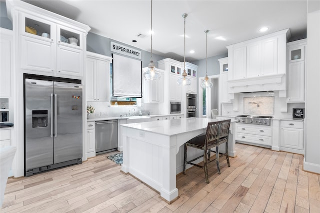 kitchen featuring a center island, white cabinets, stainless steel appliances, and light hardwood / wood-style floors