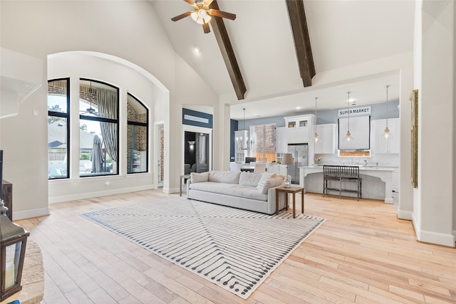 living room featuring beam ceiling, high vaulted ceiling, light wood-type flooring, and ceiling fan