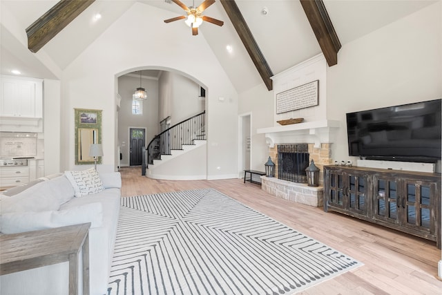 living room featuring light hardwood / wood-style floors, high vaulted ceiling, beamed ceiling, and a fireplace