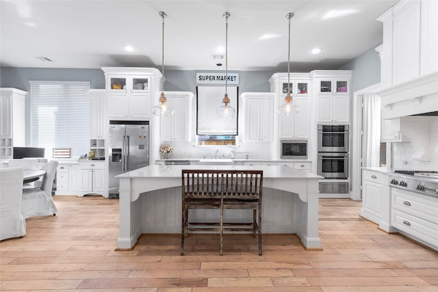 kitchen with a kitchen island, appliances with stainless steel finishes, hanging light fixtures, and white cabinets