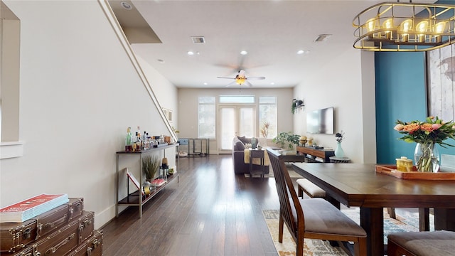 dining area with ceiling fan with notable chandelier and dark wood-type flooring