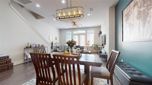 dining room with ceiling fan with notable chandelier and dark hardwood / wood-style floors