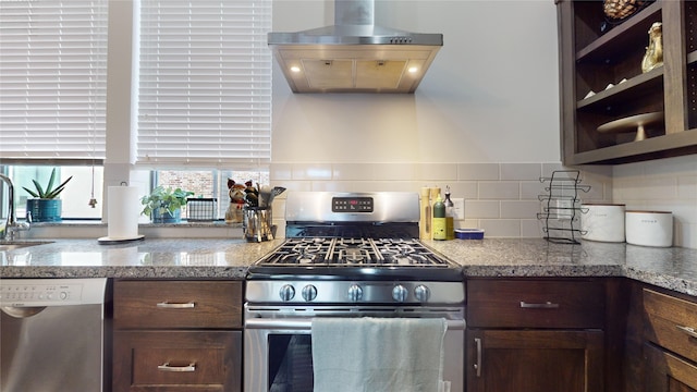 kitchen featuring tasteful backsplash, island range hood, light stone countertops, stainless steel appliances, and dark brown cabinets