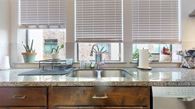 kitchen with light stone countertops, sink, and stainless steel dishwasher