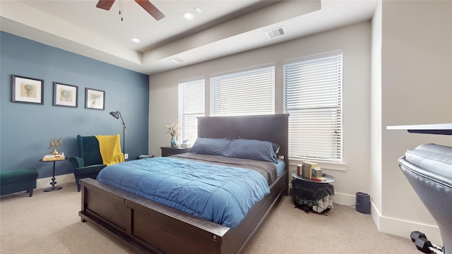 carpeted bedroom featuring a raised ceiling and ceiling fan