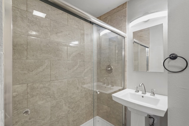 bathroom with a shower with door and sink