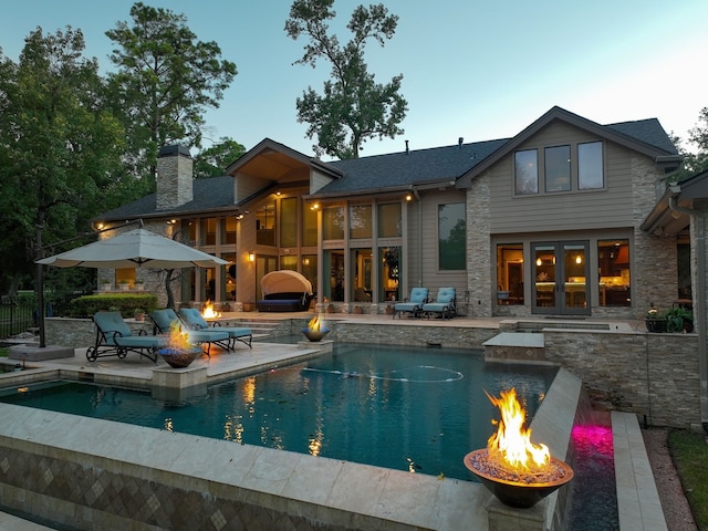 back of house with a fire pit, a swimming pool with hot tub, and a patio area