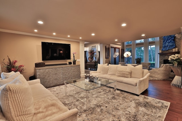 living room featuring a stone fireplace, ornamental molding, and dark hardwood / wood-style floors