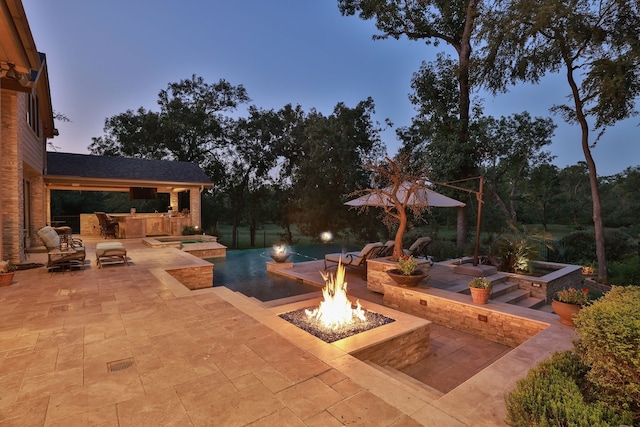 pool at dusk featuring a patio area and an outdoor fire pit