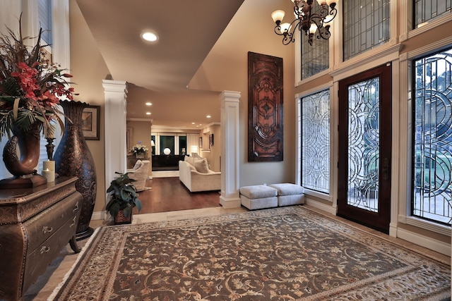 entrance foyer with a notable chandelier, hardwood / wood-style floors, high vaulted ceiling, and a wealth of natural light